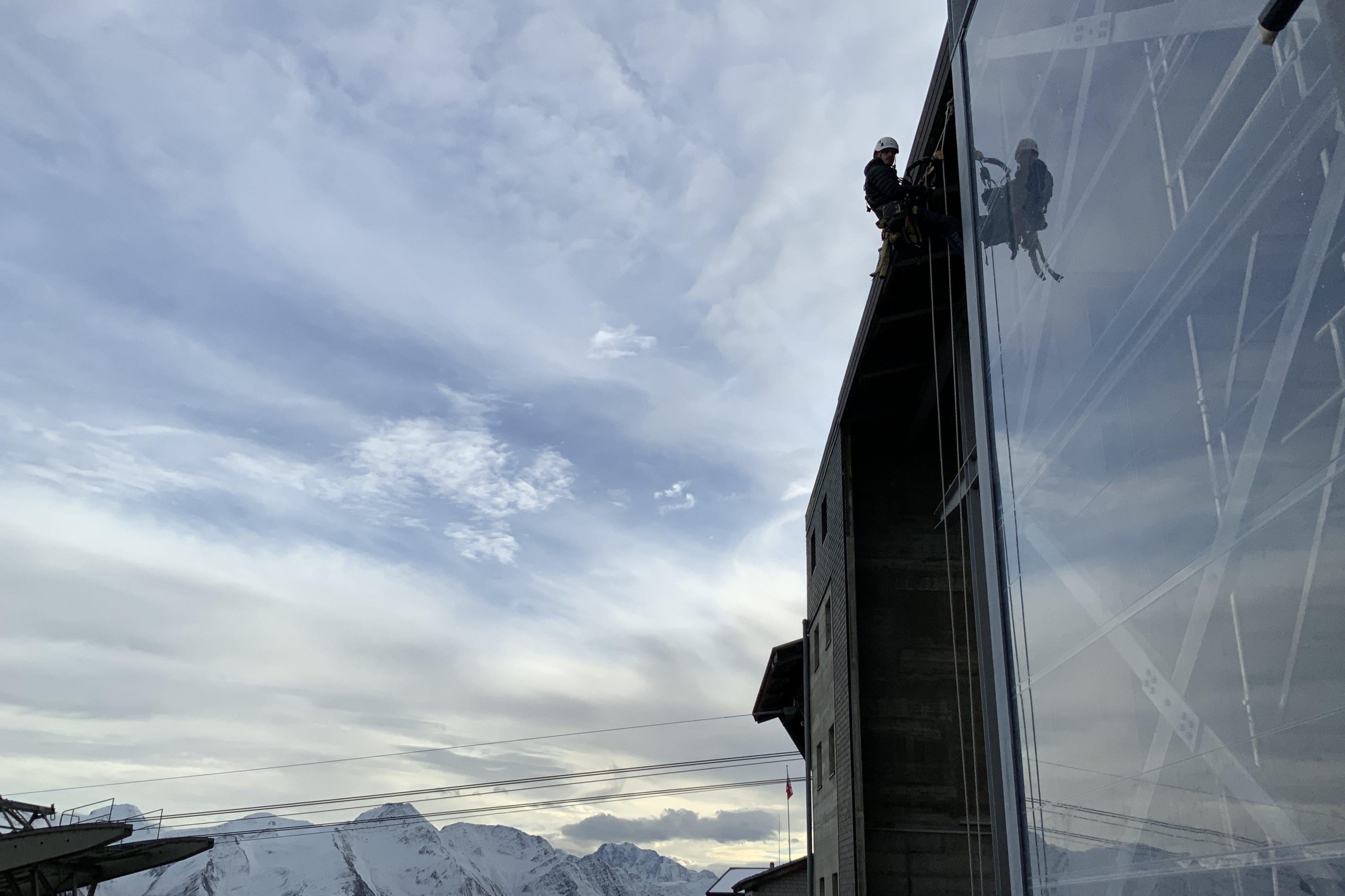 Industriekletterer mit Bergen im Hintergrunde  – Toprope